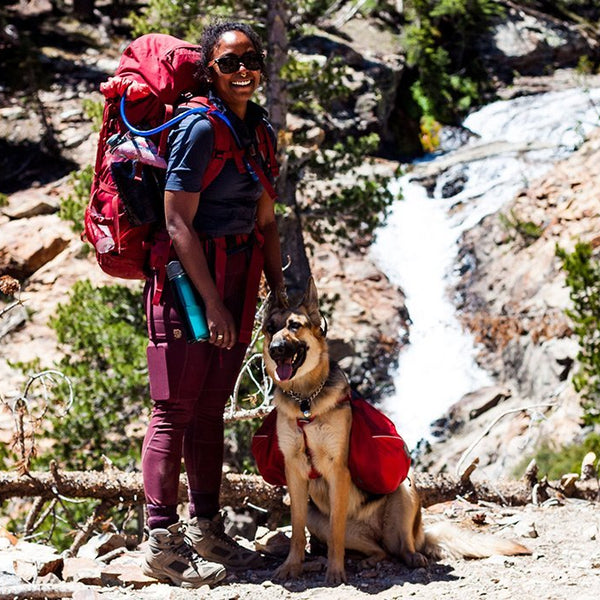Noami and Amara in backpacks by a waterfall.