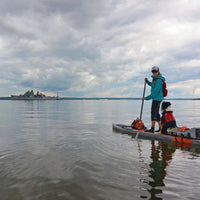 Maria paddling with her dog, her paddleboard loaded up with gear to camp.