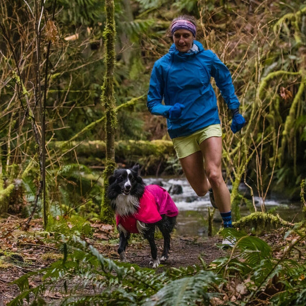 PD runs in sun shower jacket in front of Krissy on trail.
